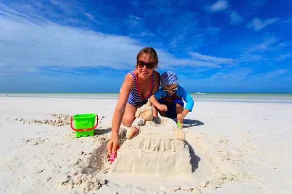 Mother and son building sand castle on summer beach