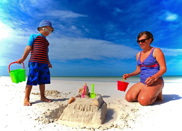 Mother and son building sand castle on summer beach