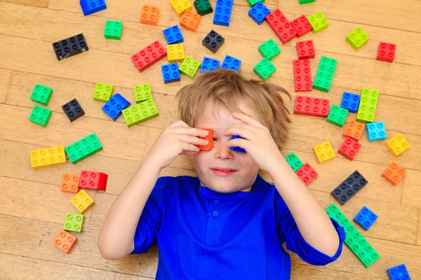 Child playing with colorful plastic blocks indoor