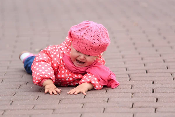 Crying little girl fall off on sidewalk