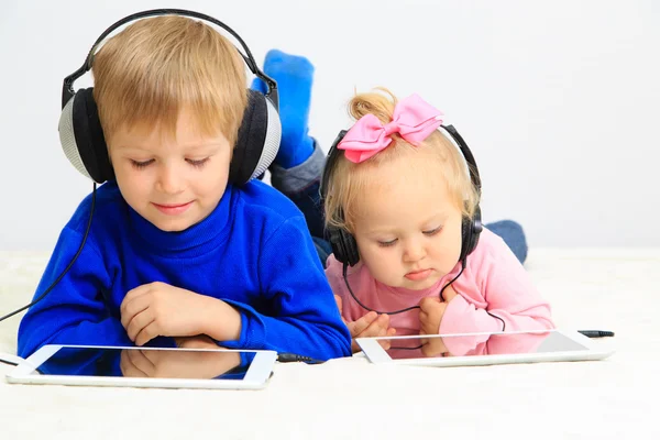 Little boy and toddler girl with headset using touch pad