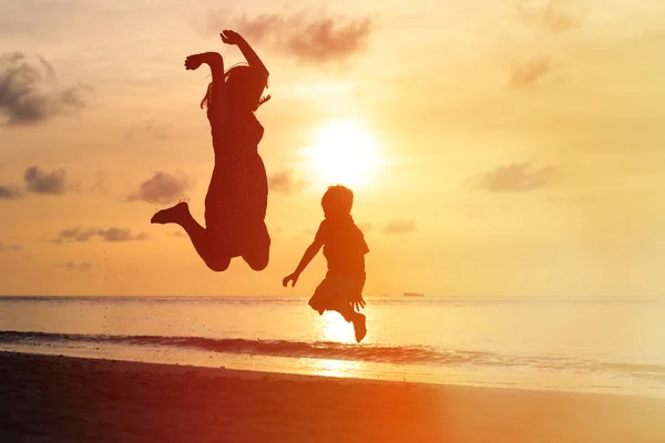 Mother and son jumping at sunset beach