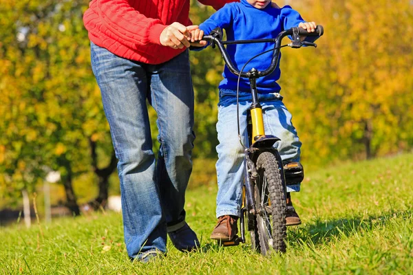 Father teaches son to ride bicycle