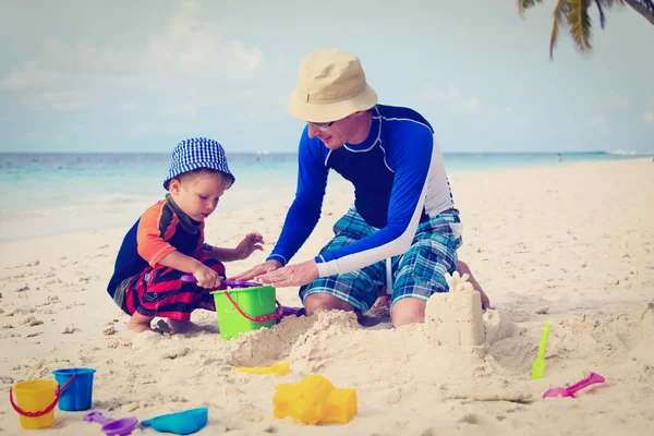 Father and son building sand castle on the beach