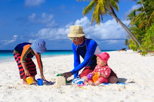 Father and kids making sand castle at tropical beach