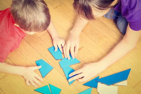 Hands of teacher and child playing with geometric shapes