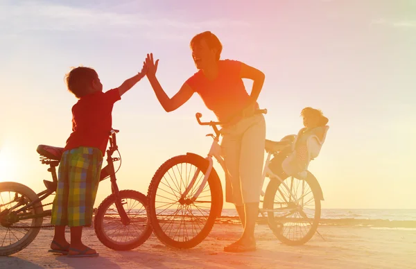 Happy mother with kids biking at sunset