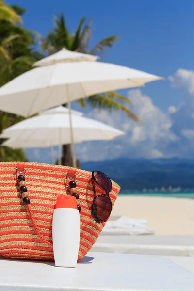Bag, sun glasses and suncream on tropical beach