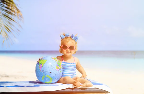 Little girl with globe and toy plane on beach