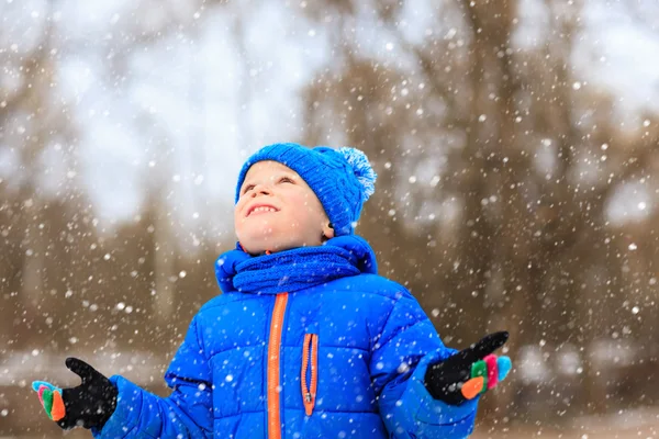 Little boy enjoy first snow in winter nature