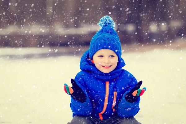 Little boy enjoy first snow in winter nature