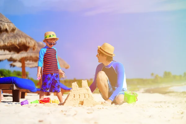 Father and son building sand castle on beach