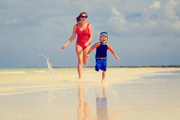 Mother and son running in water on beach