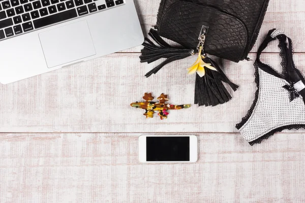 Ladies Fashion Accessories. Luxury handmade snakeskin (python) handbag, panties, frangipani flower, laptop, smartphone. Top view, flat lay, light wooden background. Free/empty space for text.