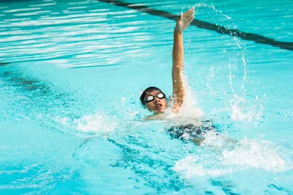 Young man swimming in backstroke in a pool.