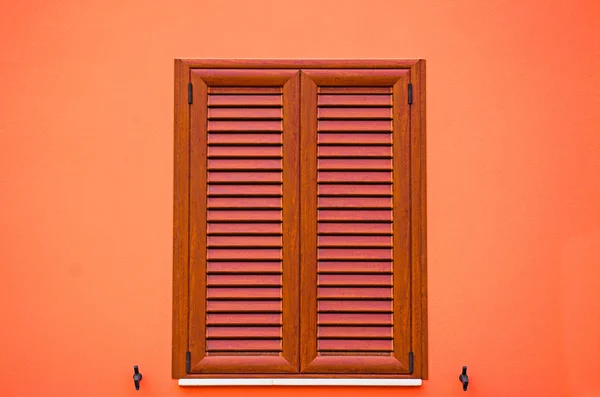 Closed window in an orange wall