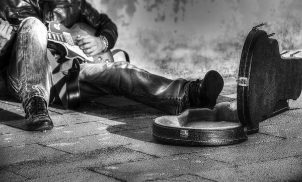 B&w guitar player in the street with an open guitar case
