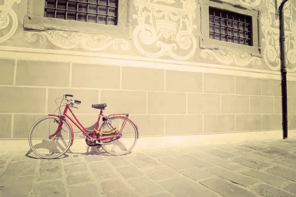 Red bike leaning against a wall in vintage tone