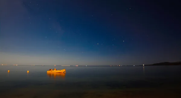 Rubber boat floating in the water at night under a starry sky