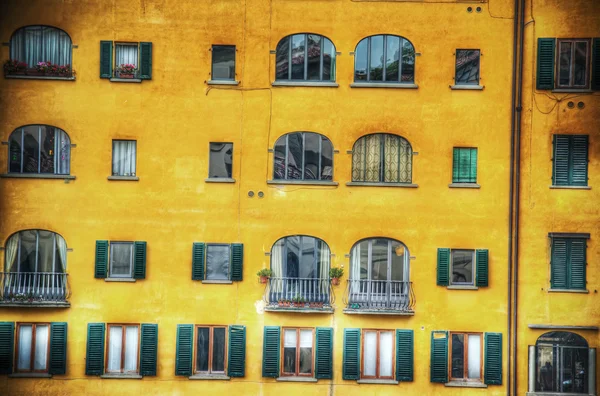 Yellow building facade with green shutters in Florence