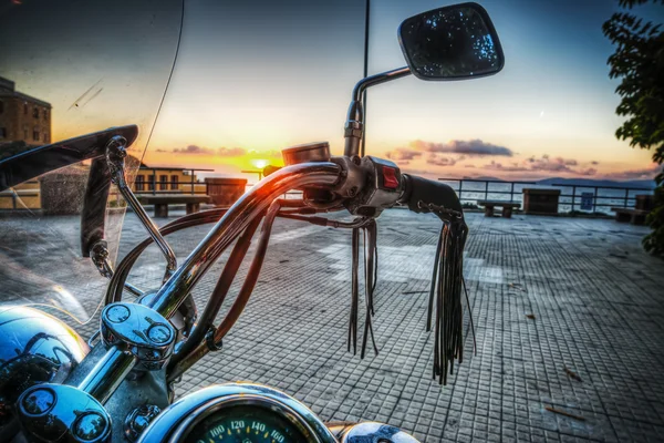 Classic motorcycle by the sea at sunset