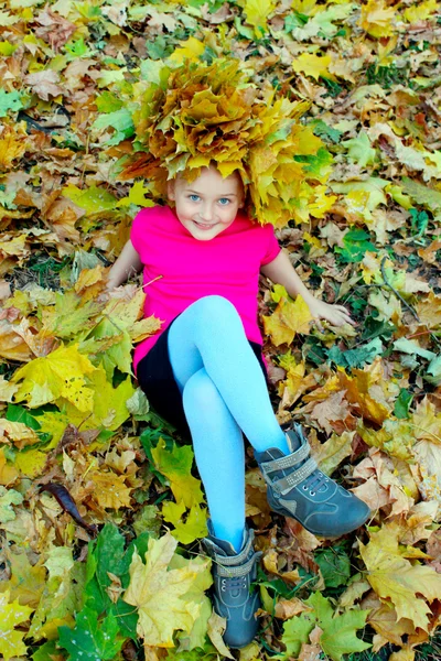 Girl with a wreath of yellow leaves lying on the leaves