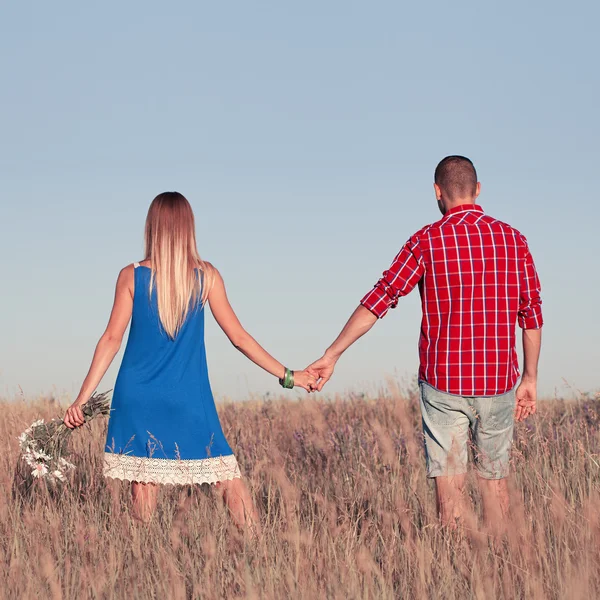 Love story. Beautiful young couple walking in meadow, outdoor