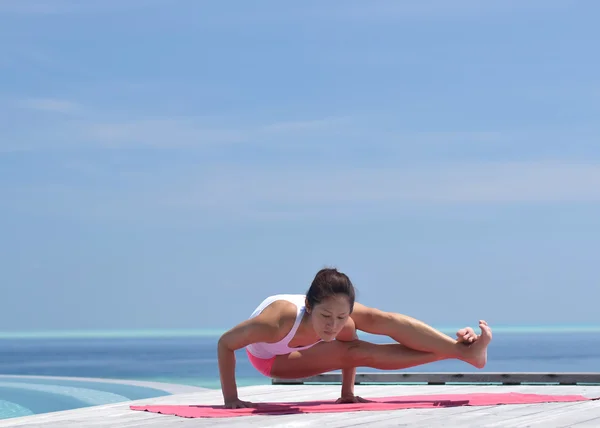 Asian chinese woman practising yoga by the sea