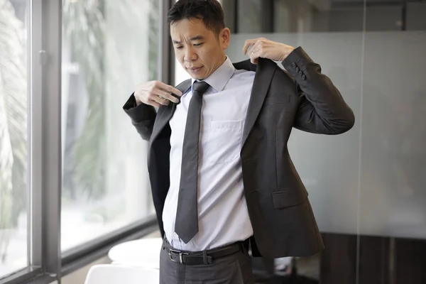 Successful asian man putting on his suit ready for meeting