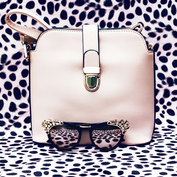 Handbags and fashion stylish sunglasses on leopard print backgro