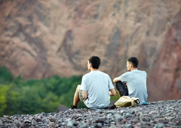 Two  men sitting on  cliff