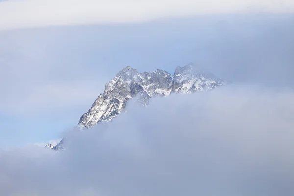 Mountain peak in the cloud-based sky