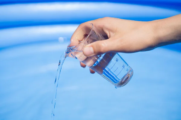 Water testing at swimming pool, laboratory glassware in hand