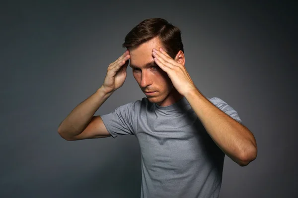 Young man in t-shirt thinking or experiencing headaches.