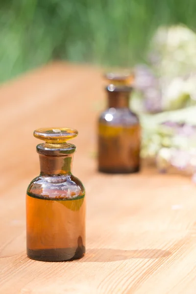 Essential oil in little bottle and medical flowers herbs