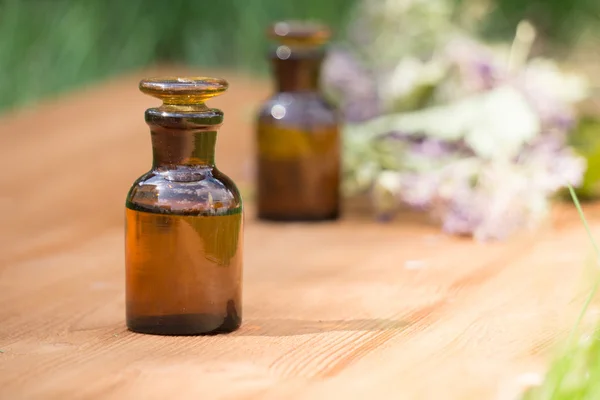 Essential oil in little bottle and medical flowers herbs