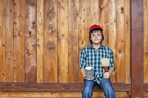 Boy finished painting wooden wall - resting