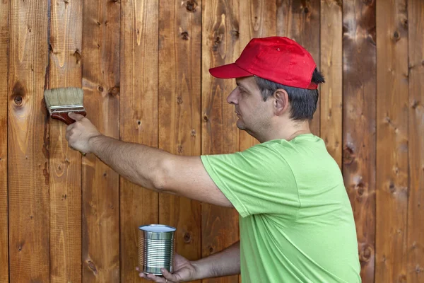 Man painting wooden wall