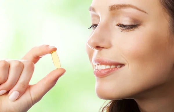 Woman with Omega 3 fish oil capsule