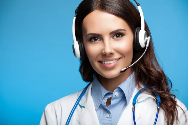 Happy smiling young doctor in headset, on blue