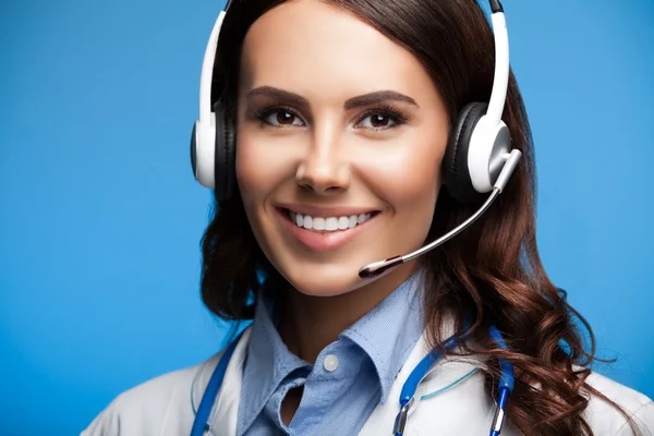 Smiling female doctor in headset, on blue