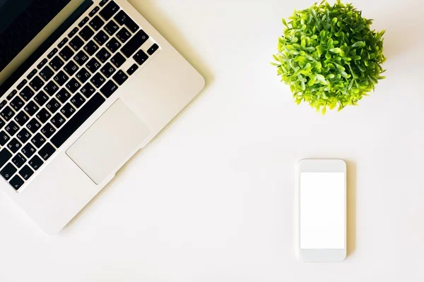 Keyboard, white phone and plant