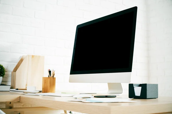 Side view of creative designer desktop with blank computer monitor, various stationery and decorative items on brick wall background. Mock up