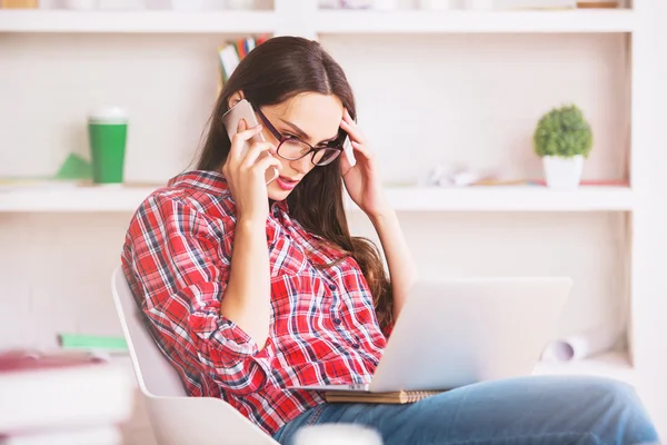 Young woman using laptop and phone