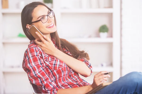 Young woman on phone taking notes