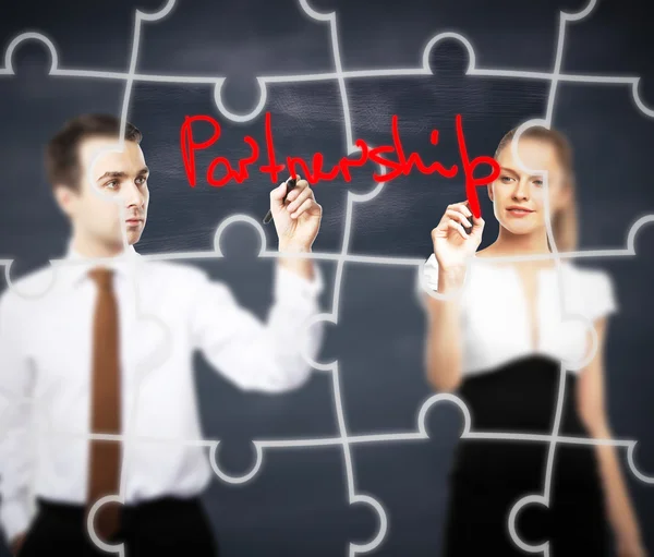 Business man and woman writing partnership on abstract blackboard background with puzzle piece pattern