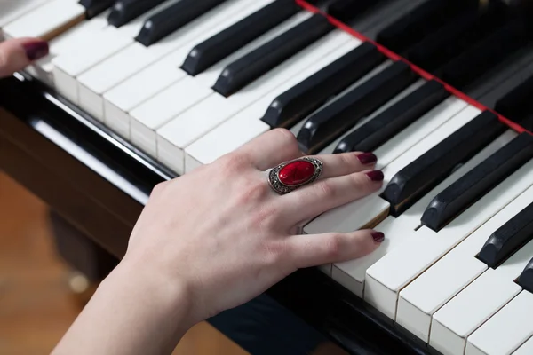 A woman with red ring playing piano