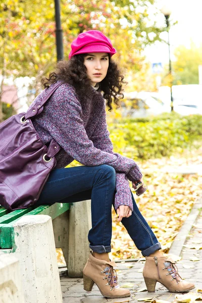 Young beautiful woman sitting on a bench in a city park