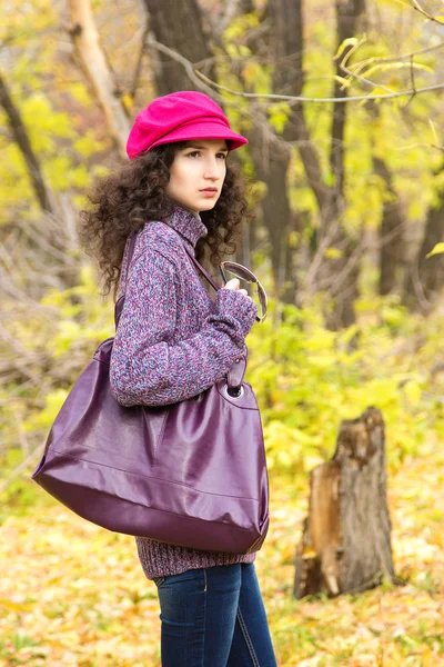 Young stylish woman with a big bag in the autumn park