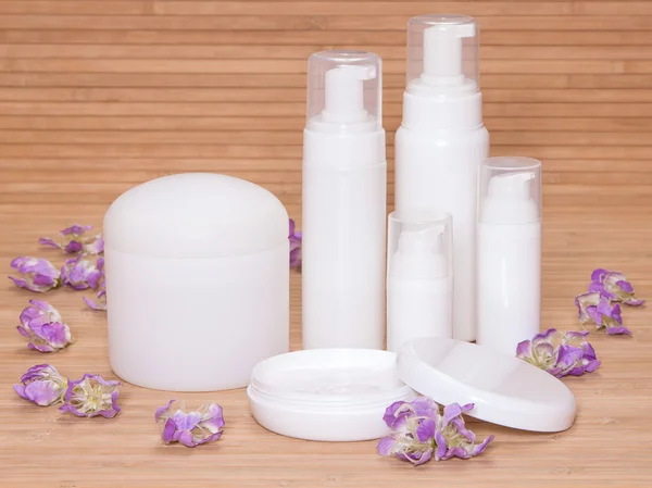 Open jar of cream and other body care cosmetics with flowers